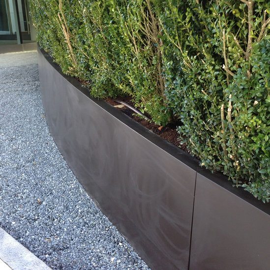 Curved, sloping steel planters for luxury development 